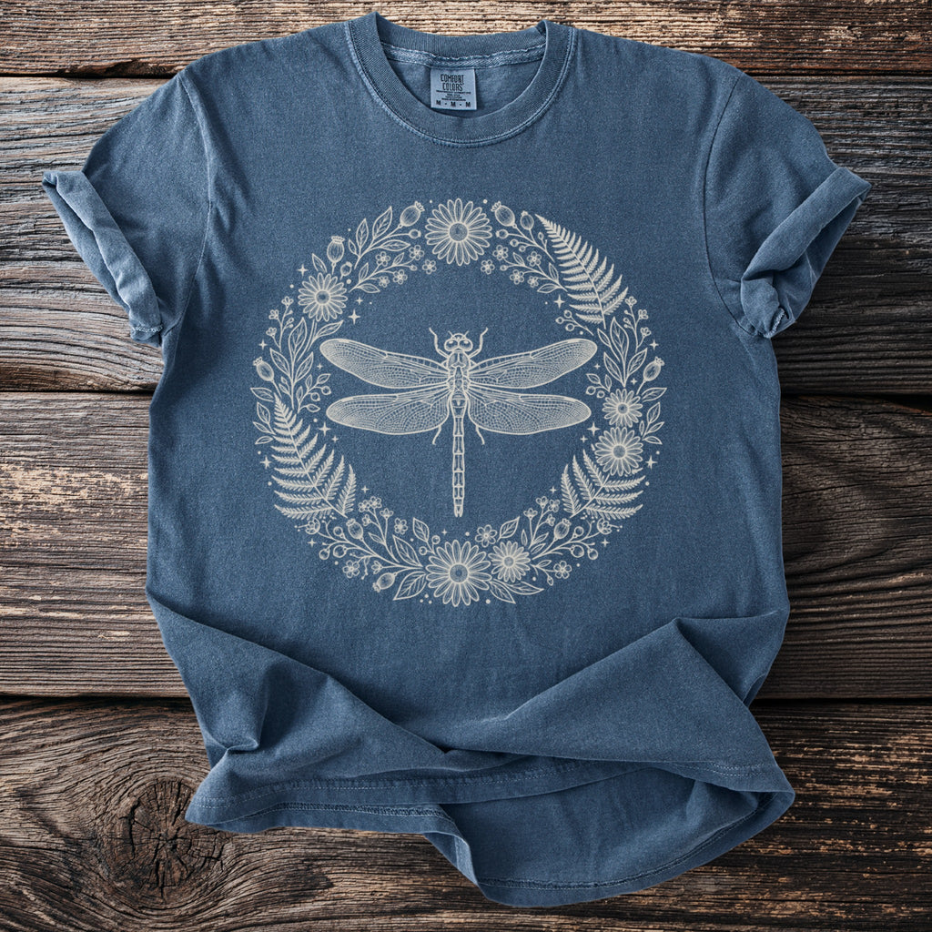 Blue t-shirt with a cream outline of a dragonfly in a floral wreath.