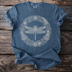 Blue t-shirt with a cream outline of a dragonfly in a floral wreath.