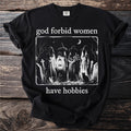 Black t-shirt with "god forbid women have hobbies" text and witch illustration.