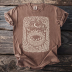 Brown t-shirt with a cream intricate forest, moon, and fairy design.