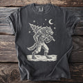 Pepper gray t-shirt with a cream folk-cut print: a snarling werewolf in torn trousers walks through the snow with a fir tree over his shoulder.