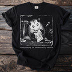 Black t-shirt with a distressed print of an opossum eating from a trash can, text reads "everything is technically edible".