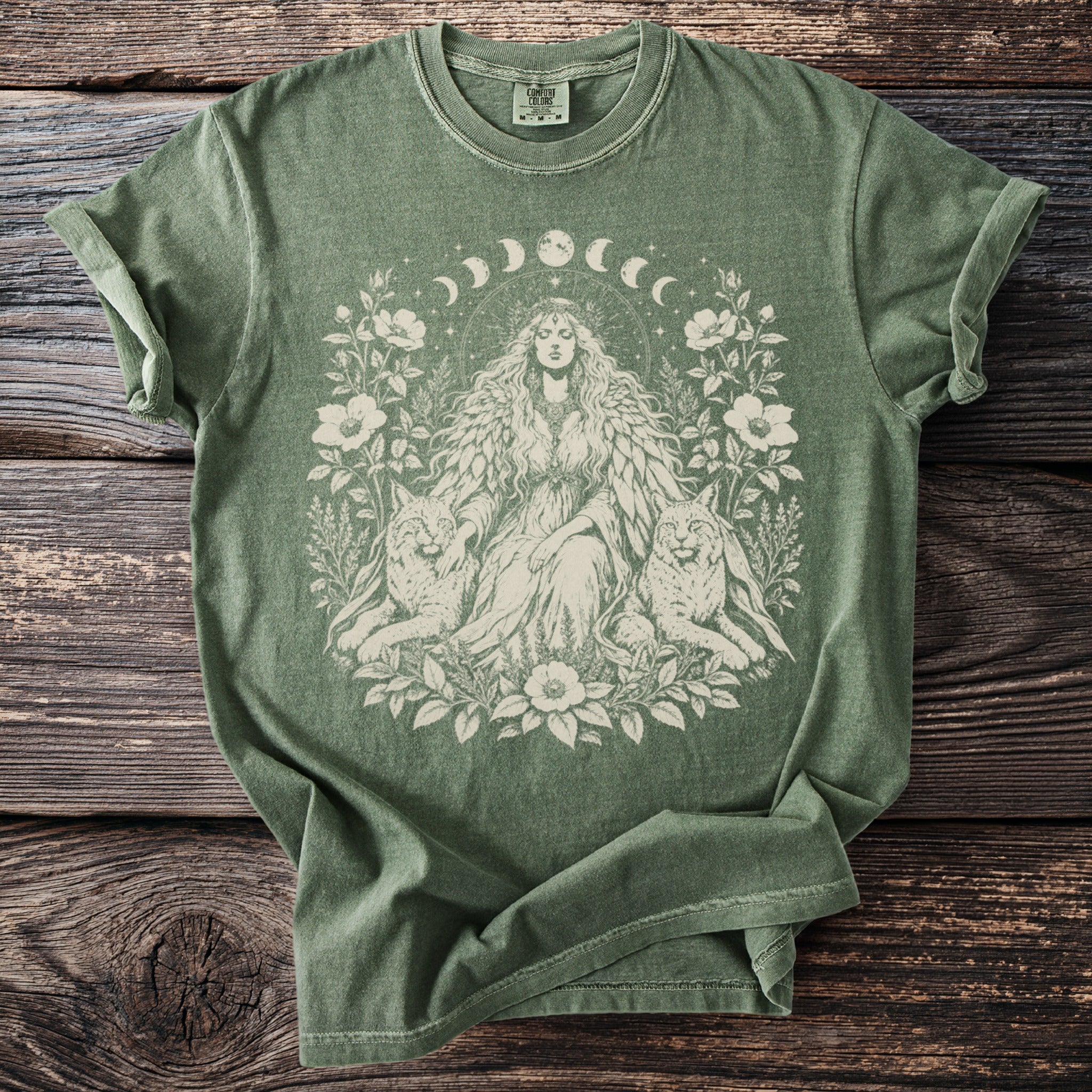 Green t-shirt with a celestial goddess, wolves, and floral design.