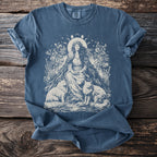 Blue t-shirt with illustration of crowned woman sitting between two foxes and floral elements.