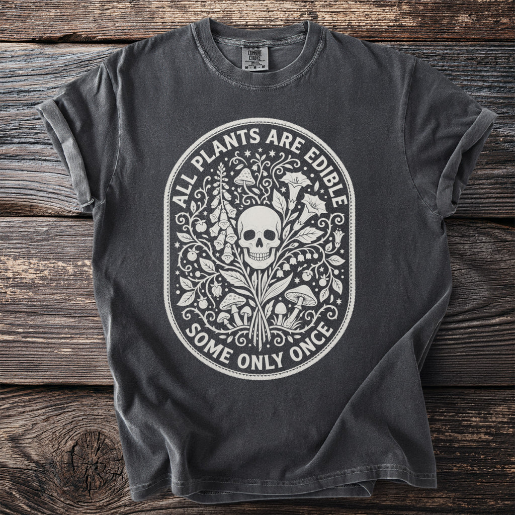 Dark t-shirt with white graphic of skull and plants with text "ALL PLANTS ARE EDIBLE SOME ONLY ONCE".