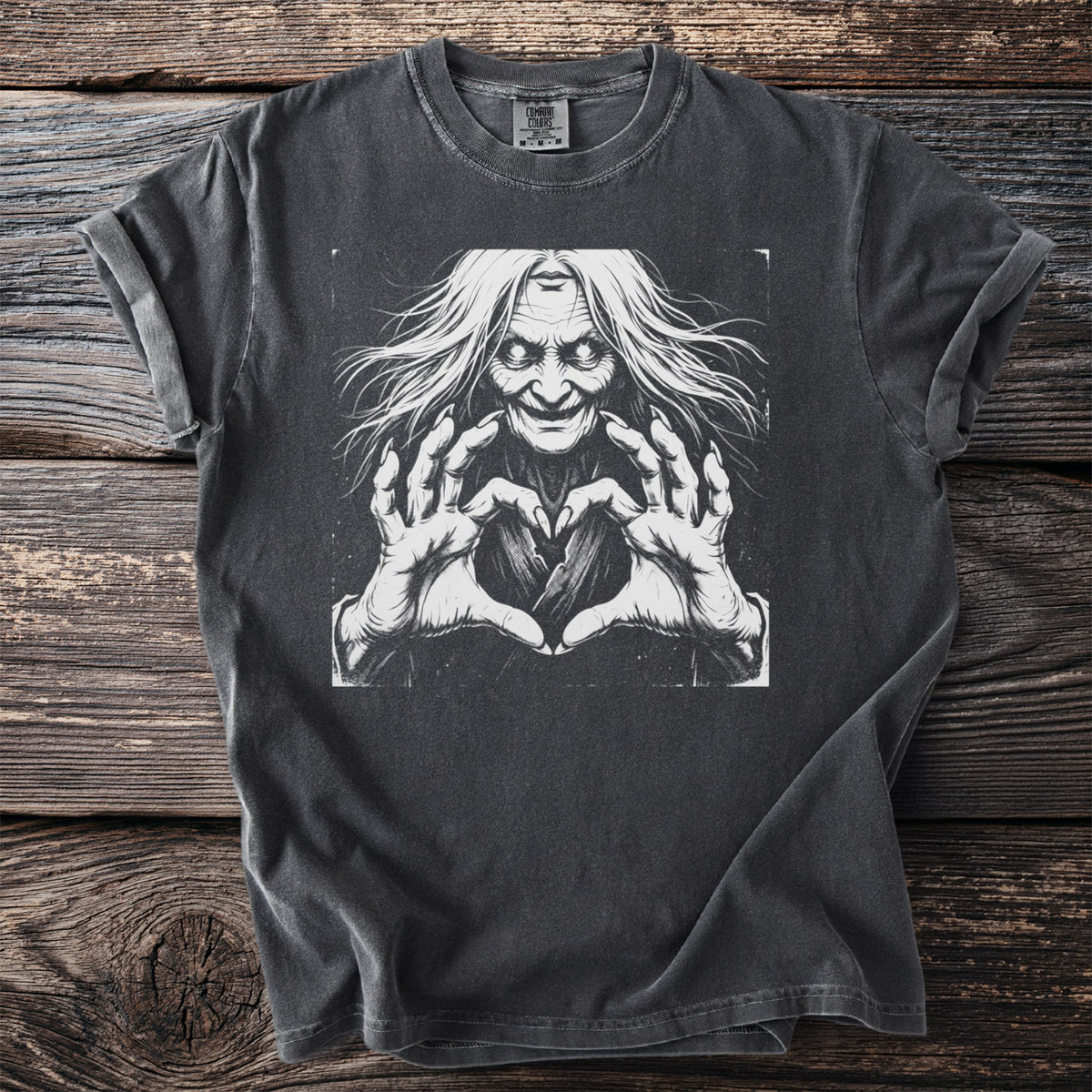 Dark t-shirt with a black and white illustration of a witch making a heart shape with her hands.
