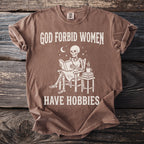 Brown t-shirt with skeleton reading and text "God forbid women have hobbies".