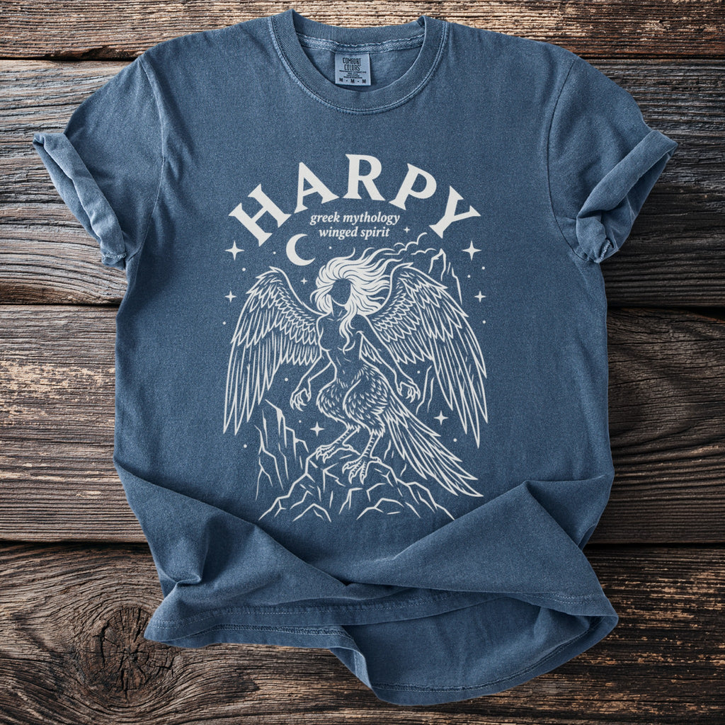 Blue t-shirt with white line art of a harpy, Greek mythology, winged spirit above mountains.