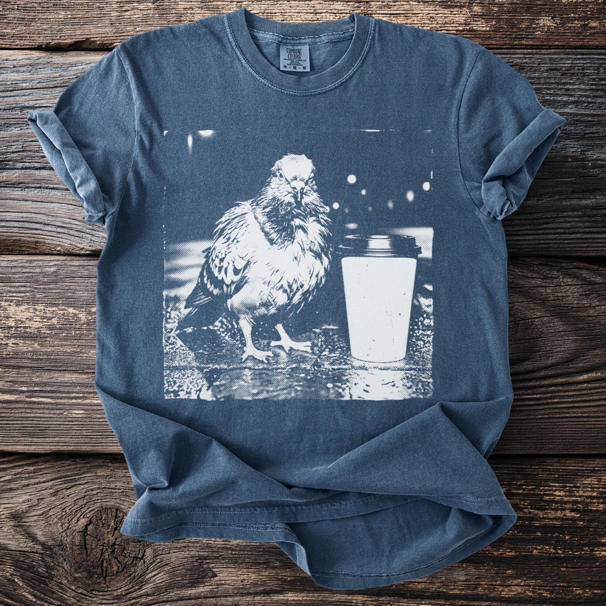 Blue t-shirt with a graphic of a pigeon next to a coffee cup.