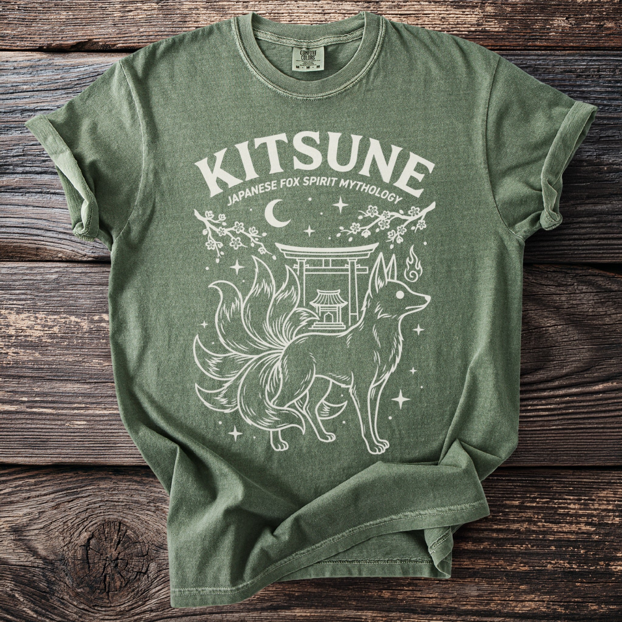 Green t-shirt with white graphic of a nine-tailed fox and Japanese shrine.