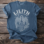 Blue t-shirt with "Lilith first wife demoness mythology" and an illustration of a winged figure.