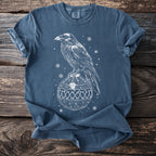 Blue t-shirt with white outline of raven perched on an ornate Christmas ornament.