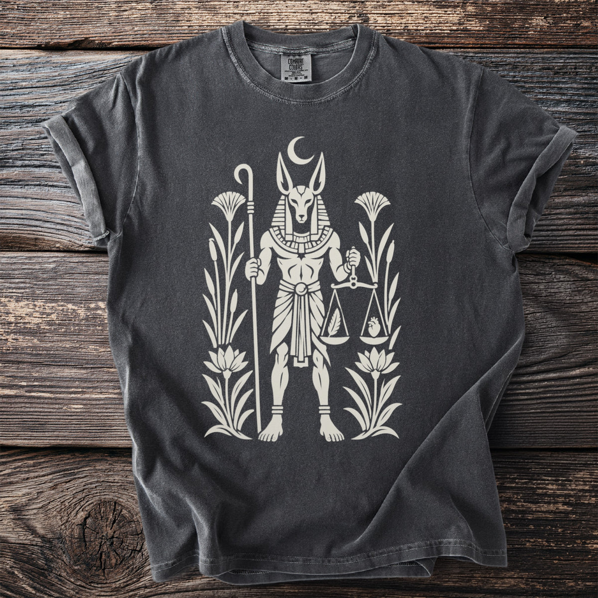 Dark grey t-shirt featuring Anubis with scales and plants in cream print.