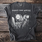Dark gray t-shirt with white graphic and text "support local goblins".
