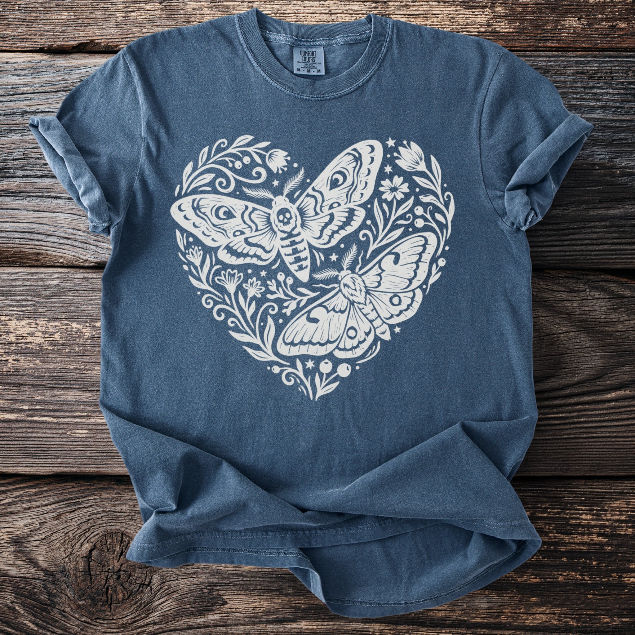 Blue t-shirt with a white floral heart design featuring two moths.