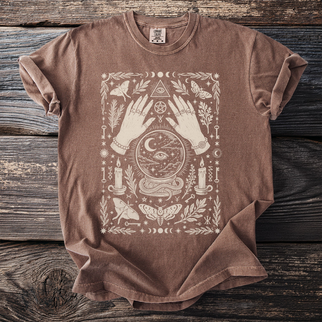Brown t-shirt with occult graphic of hands, crystal ball, moths, and moon phases.