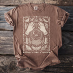 Brown t-shirt with occult graphic of hands, crystal ball, moths, and moon phases.