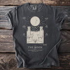 Dark grey t-shirt with "The Moon" artwork depicting a crescent moon, towers, wolf, dog, and lobster.