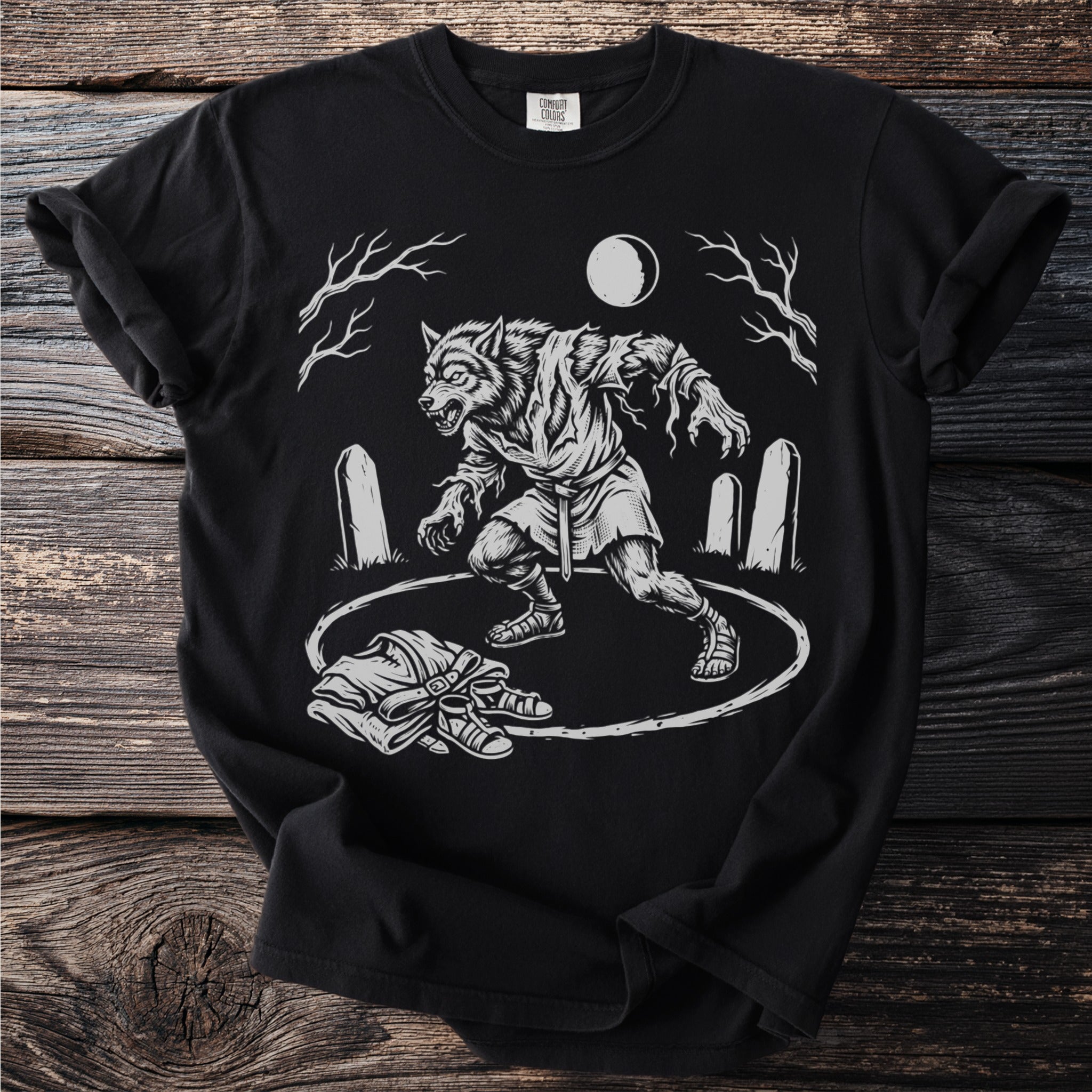 Werewolf transforming in a graveyard under a full moon, with clothes and shoes on the ground.