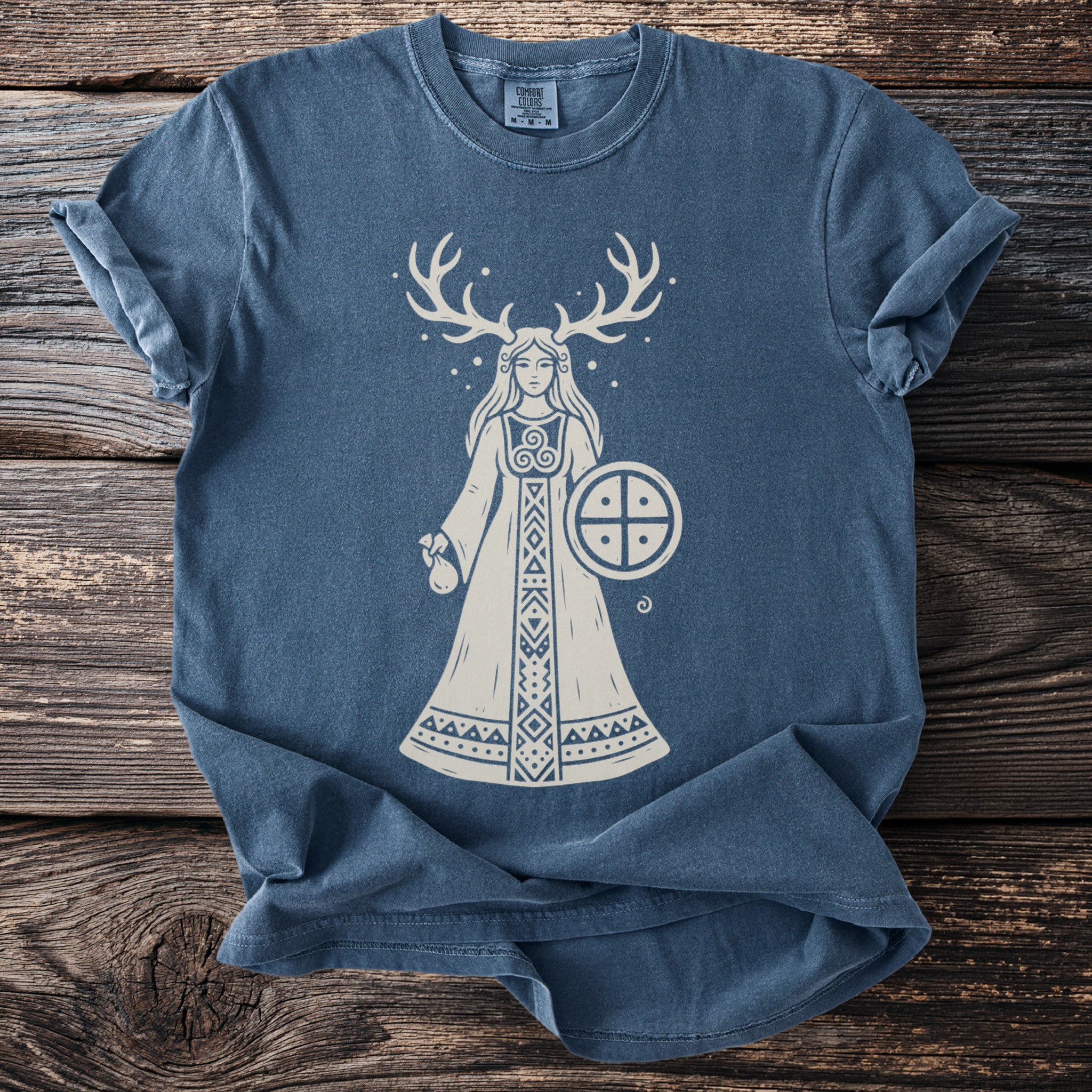 Blue t-shirt with white illustration of a woman with antlers holding a shield.