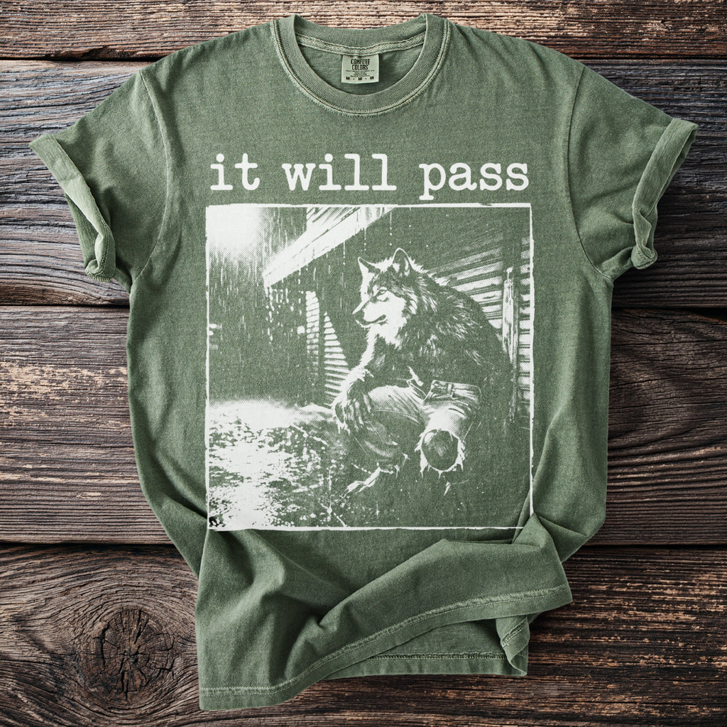 Green t-shirt with "it will pass" and a wolf in the rain graphic.