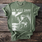 Green t-shirt with "it will pass" and a wolf in the rain graphic.