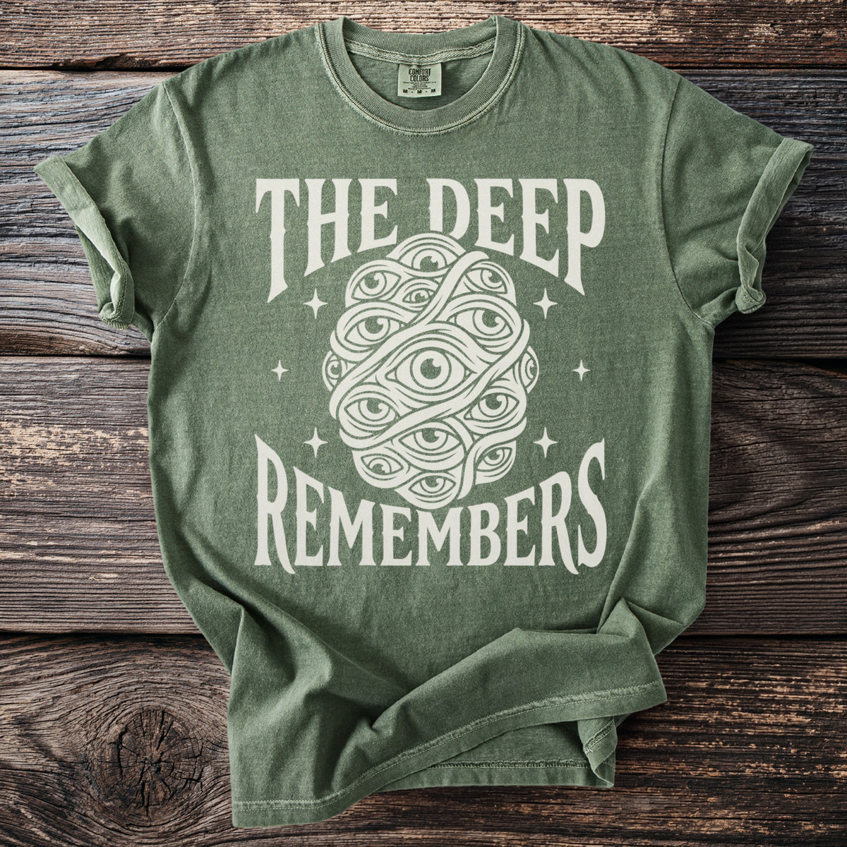 Green t-shirt with "THE DEEP REMEMBERS" text and an eye cluster graphic.