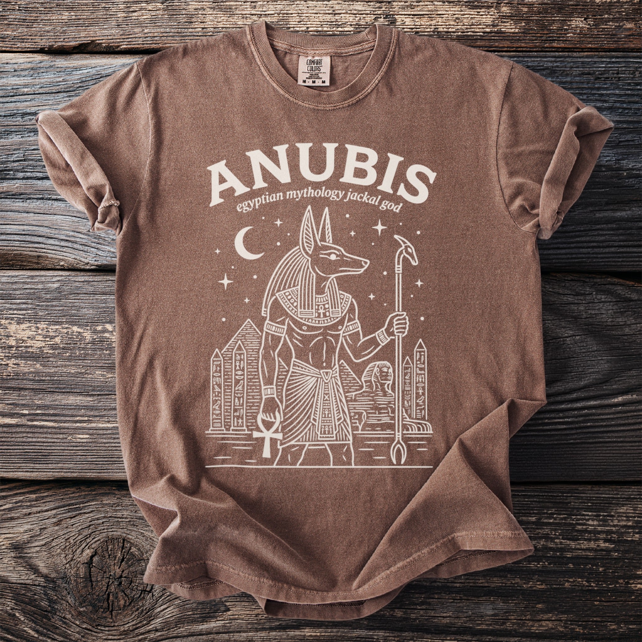 Brown t-shirt with white outline of Anubis, pyramids, and sphinx.