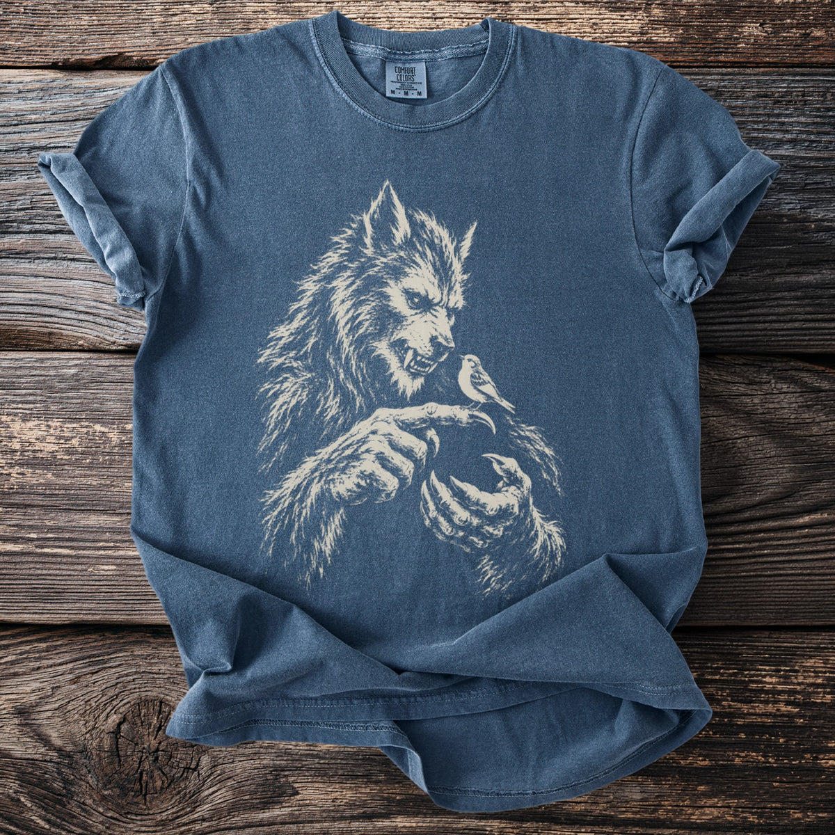 Blue t-shirt with a cream graphic of a werewolf holding a bird on its finger.