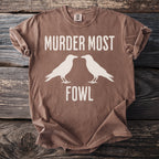 Brown t-shirt with "MURDER MOST FOWL" and two white birds.