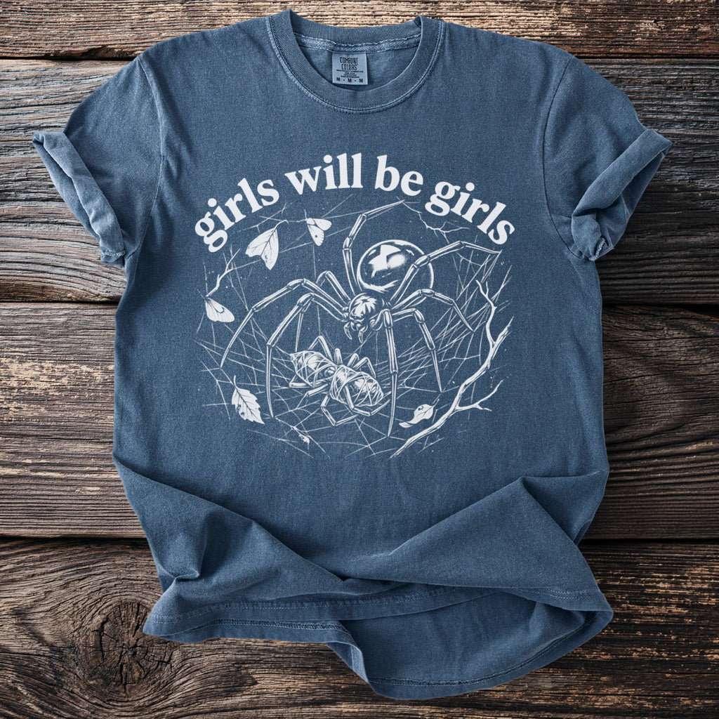 Blue t-shirt with white graphic of spider, prey, and text "girls will be girls".