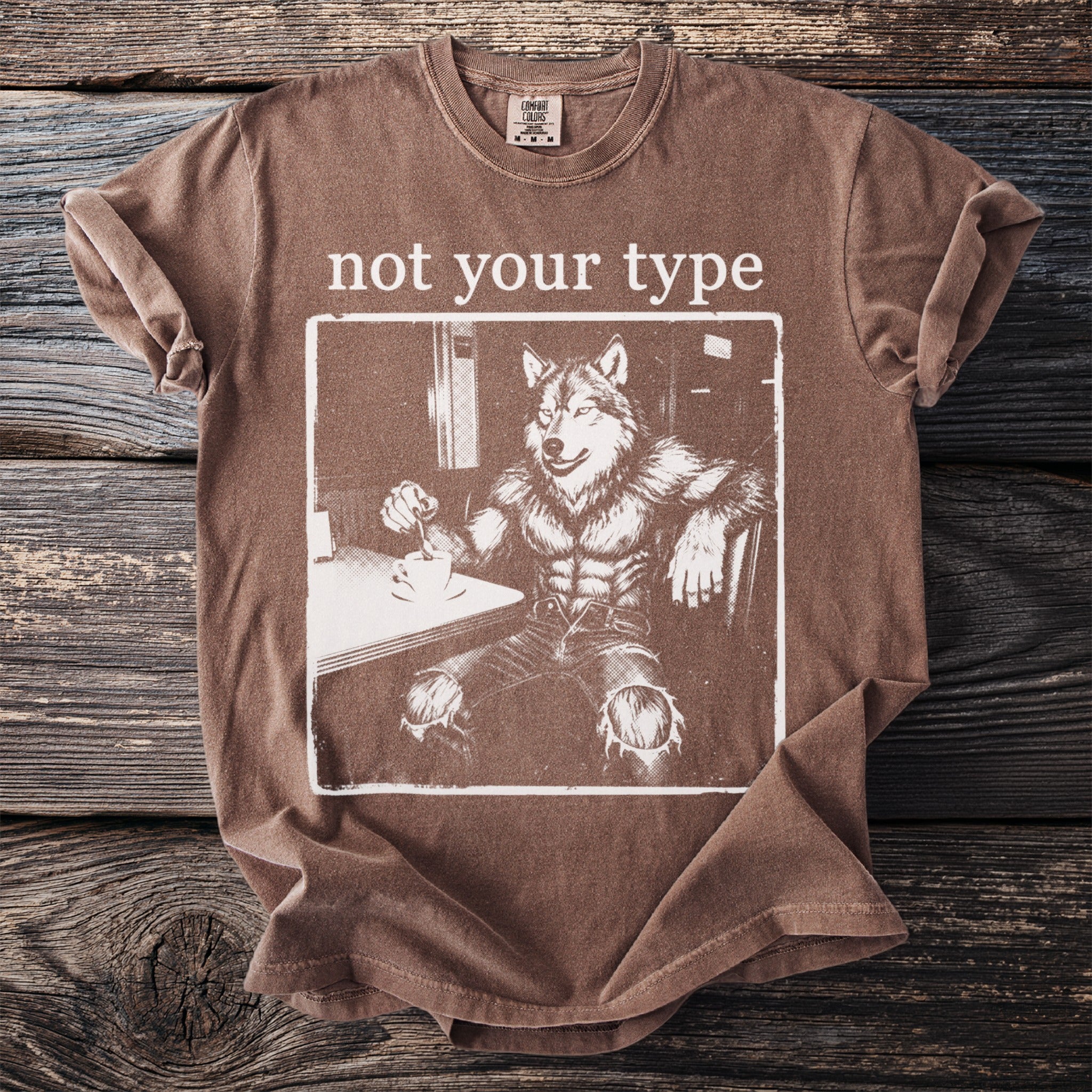 Brown t-shirt with a graphic of a wolfman drinking coffee and the text "not your type."