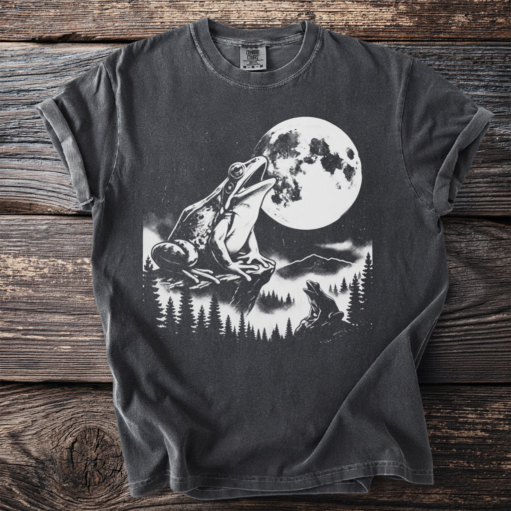 T-shirt with graphic of frogs and moon in a forest landscape.