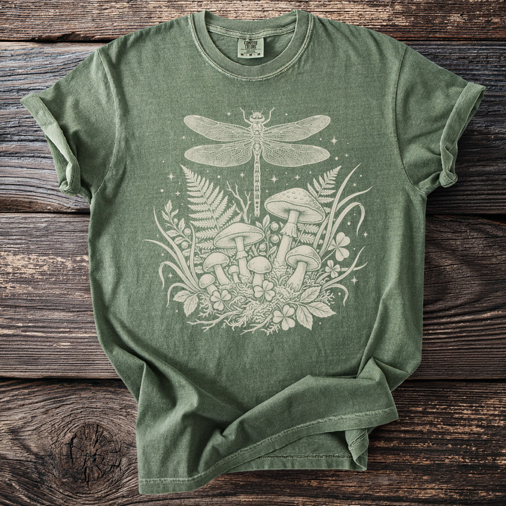 Green t-shirt with cream dragonfly, mushroom, and foliage graphic.
