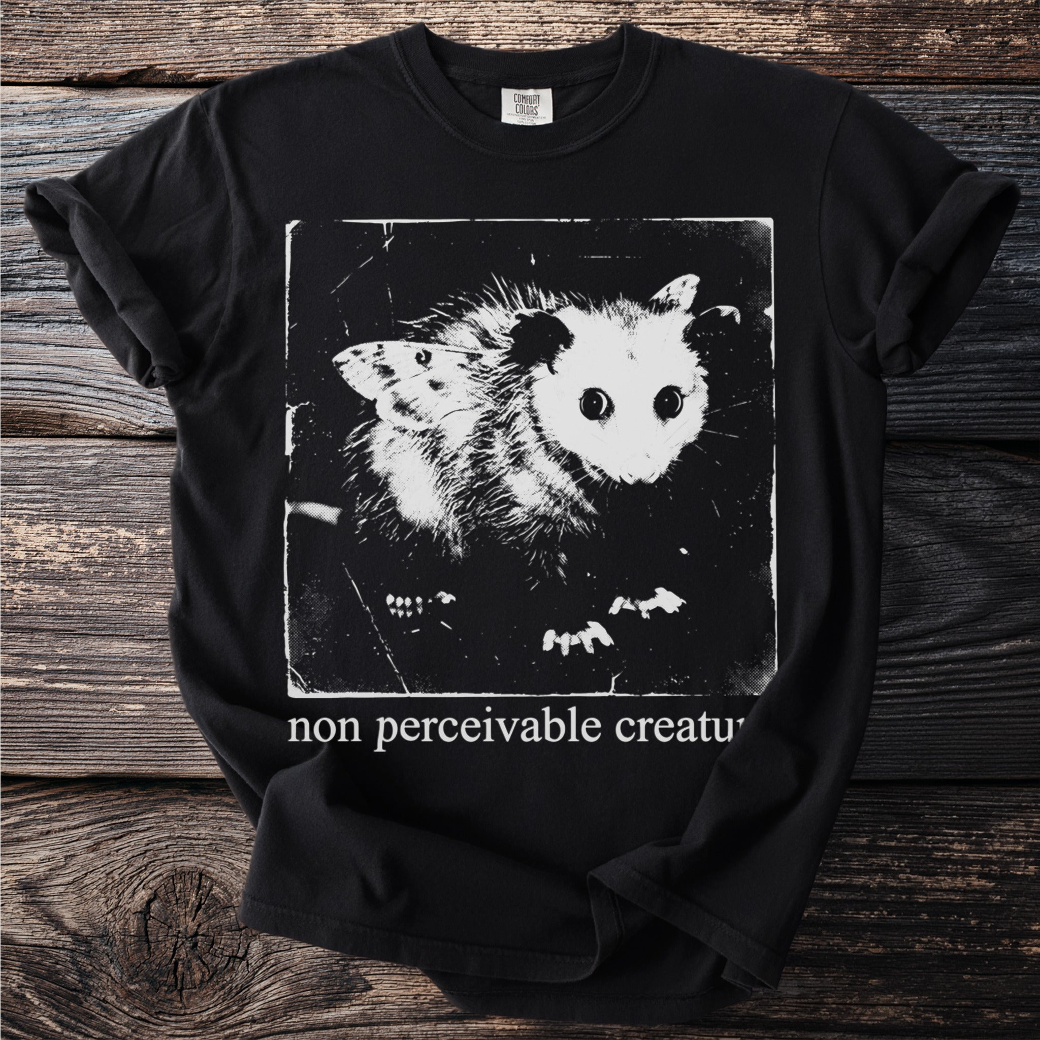 Black T shirt with an opossum and the text “non perceivable creature”.