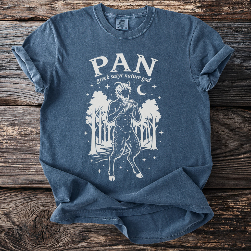 Blue t-shirt with white graphic of Pan playing pipes in a forest setting.