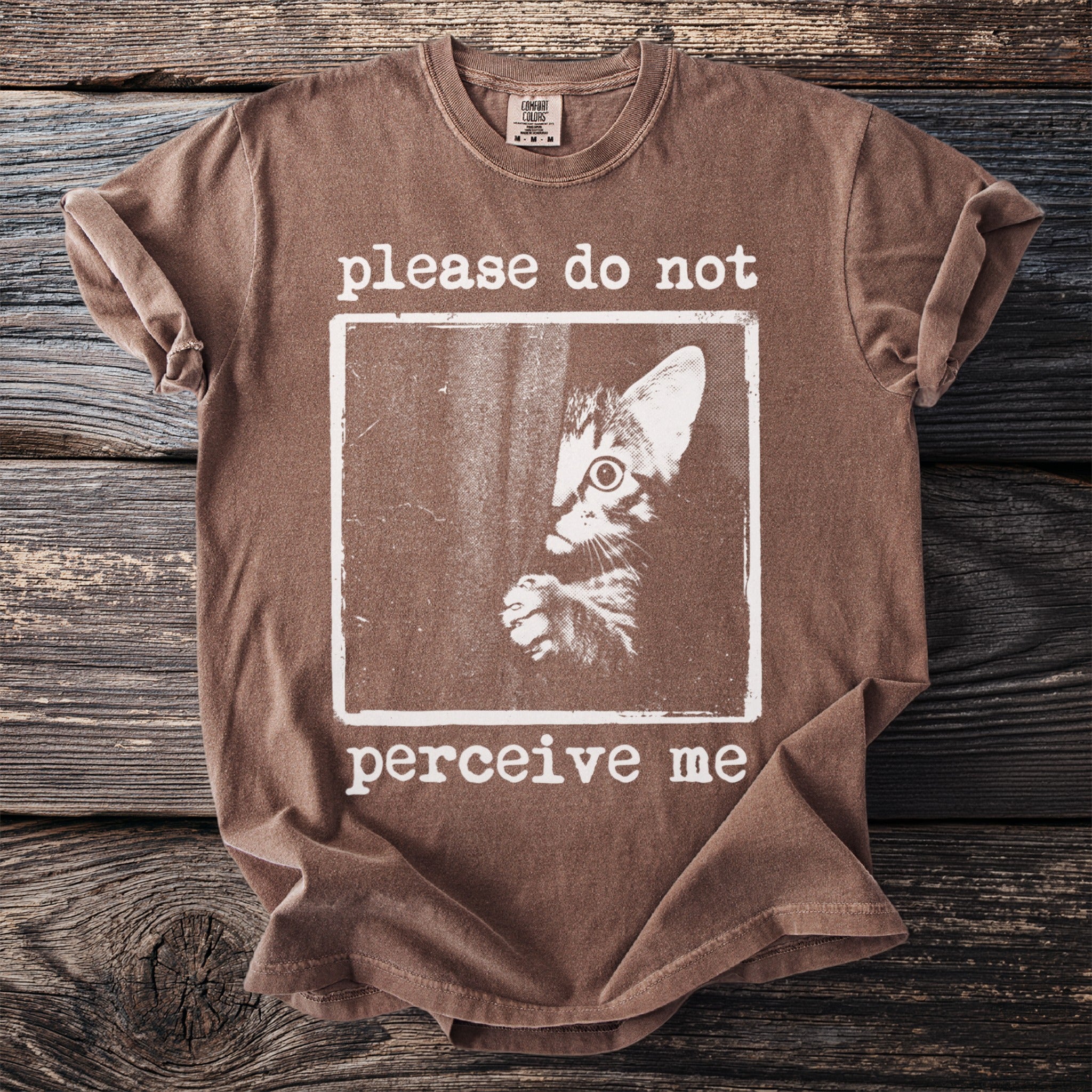 Brown t-shirt with a kitten graphic and the text "please do not perceive me."