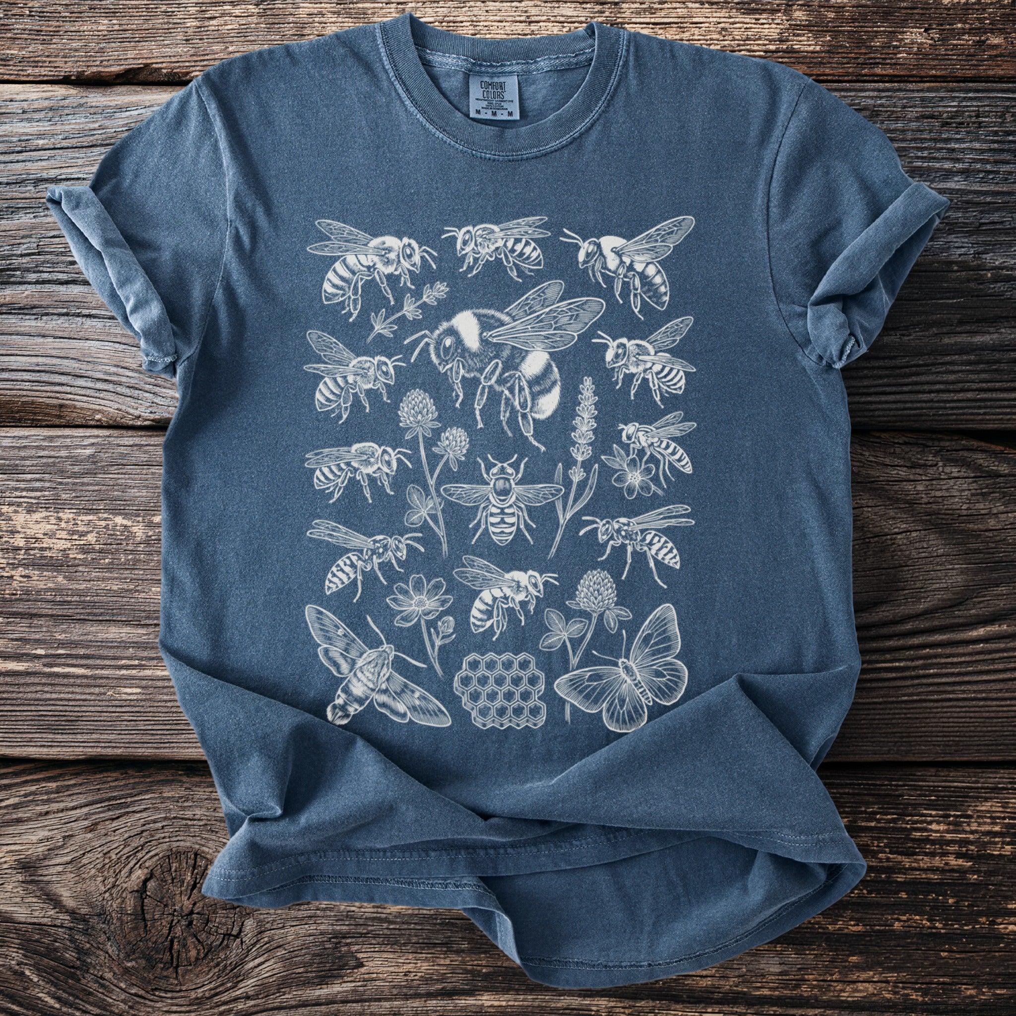 Blue t-shirt with a white line drawing of bees, butterflies, moths, clover, and honeycomb.