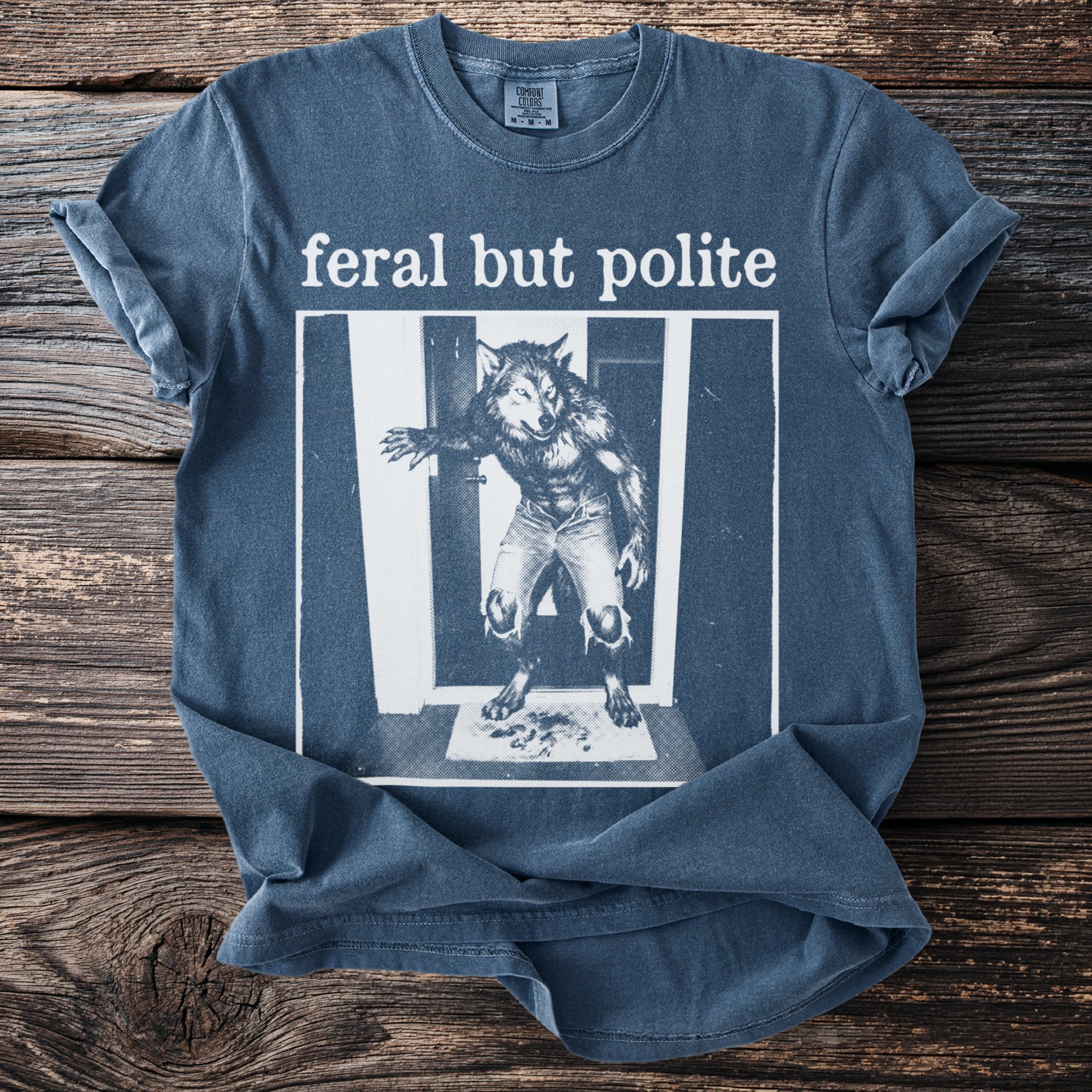 Blue t-shirt with "feral but polite" text and a werewolf graphic.