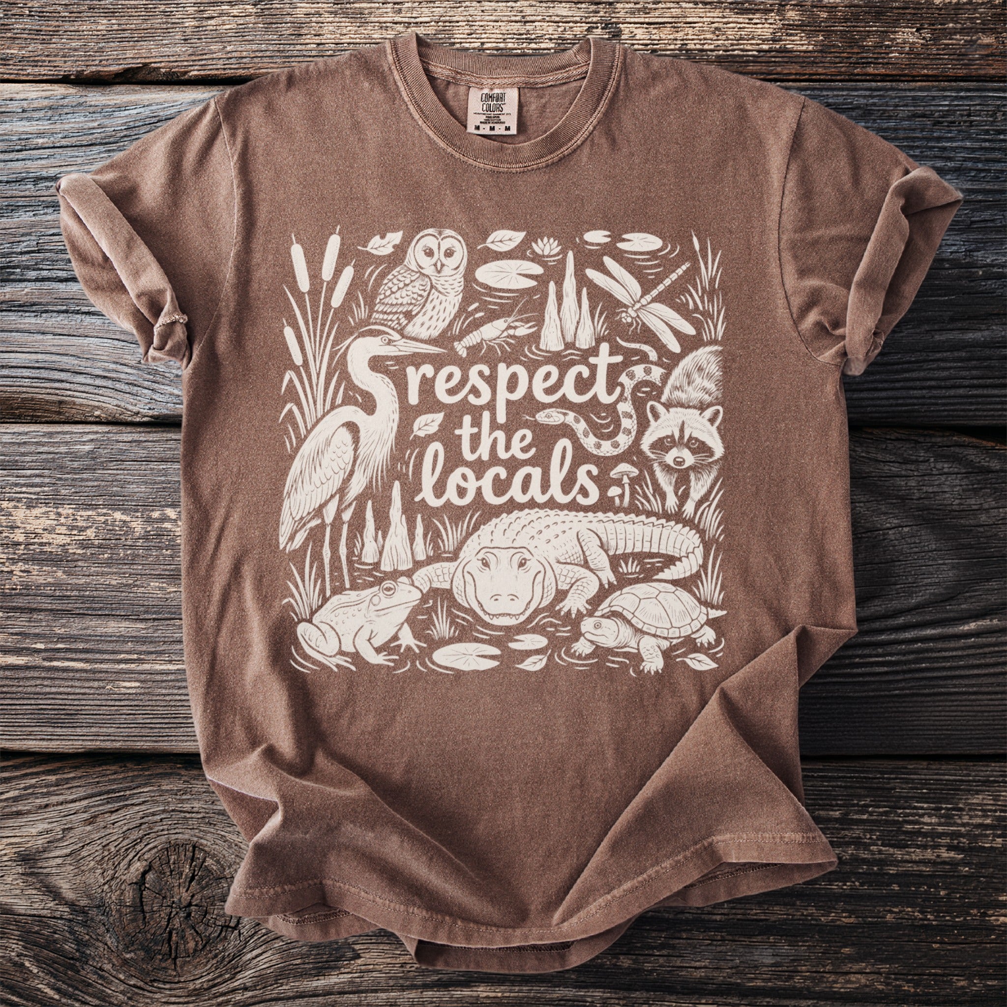 Brown t-shirt with white graphic of "respect the locals" and local wildlife.