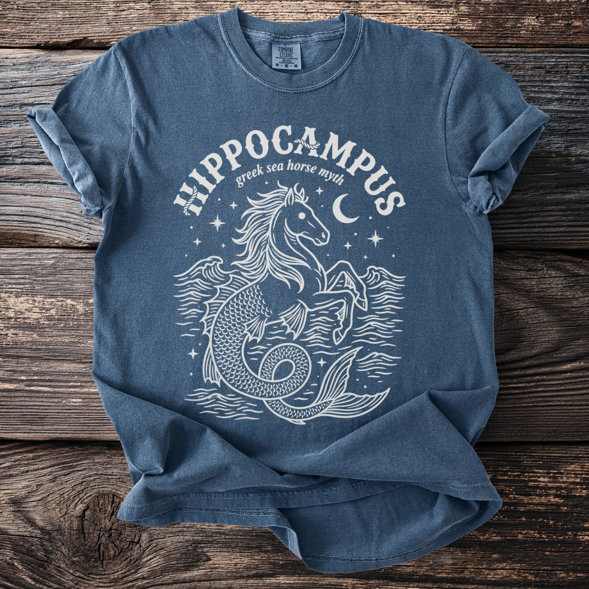 Blue t-shirt with white line art of a hippocampus, waves, moon, and stars.