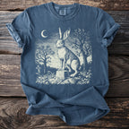 Rabbit sitting on a tombstone under a crescent moon with surrounding trees.