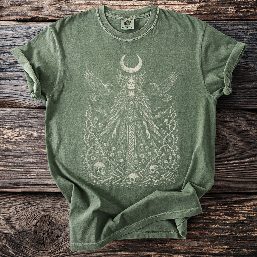 Green t-shirt with a woman, moon, ravens, skulls, and vines graphic.