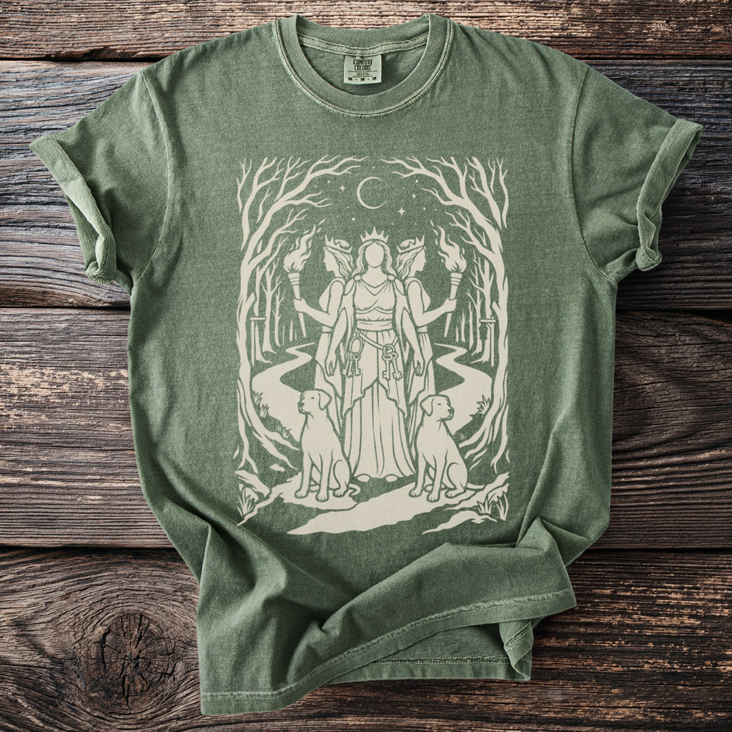 Green t-shirt with a minimalist design of three goddesses in a forest with torches and dogs.