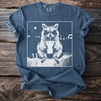 T-shirt with graphic of raccoon wearing sunglasses drinking from a cup.