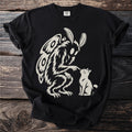 Black t-shirt with a mothman touching a cat's nose.