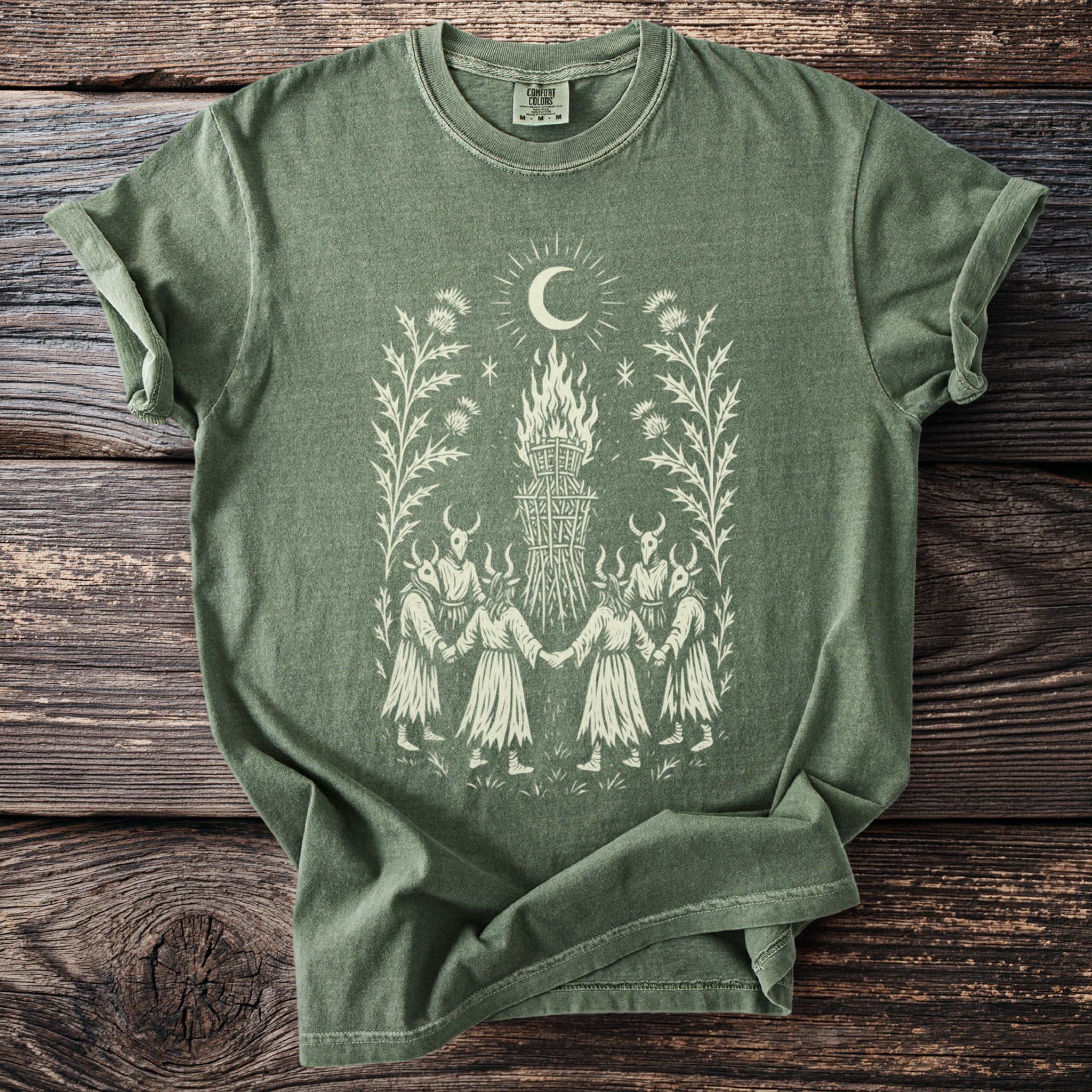 Green t-shirt with a cream graphic of figures in a circle around a bonfire.