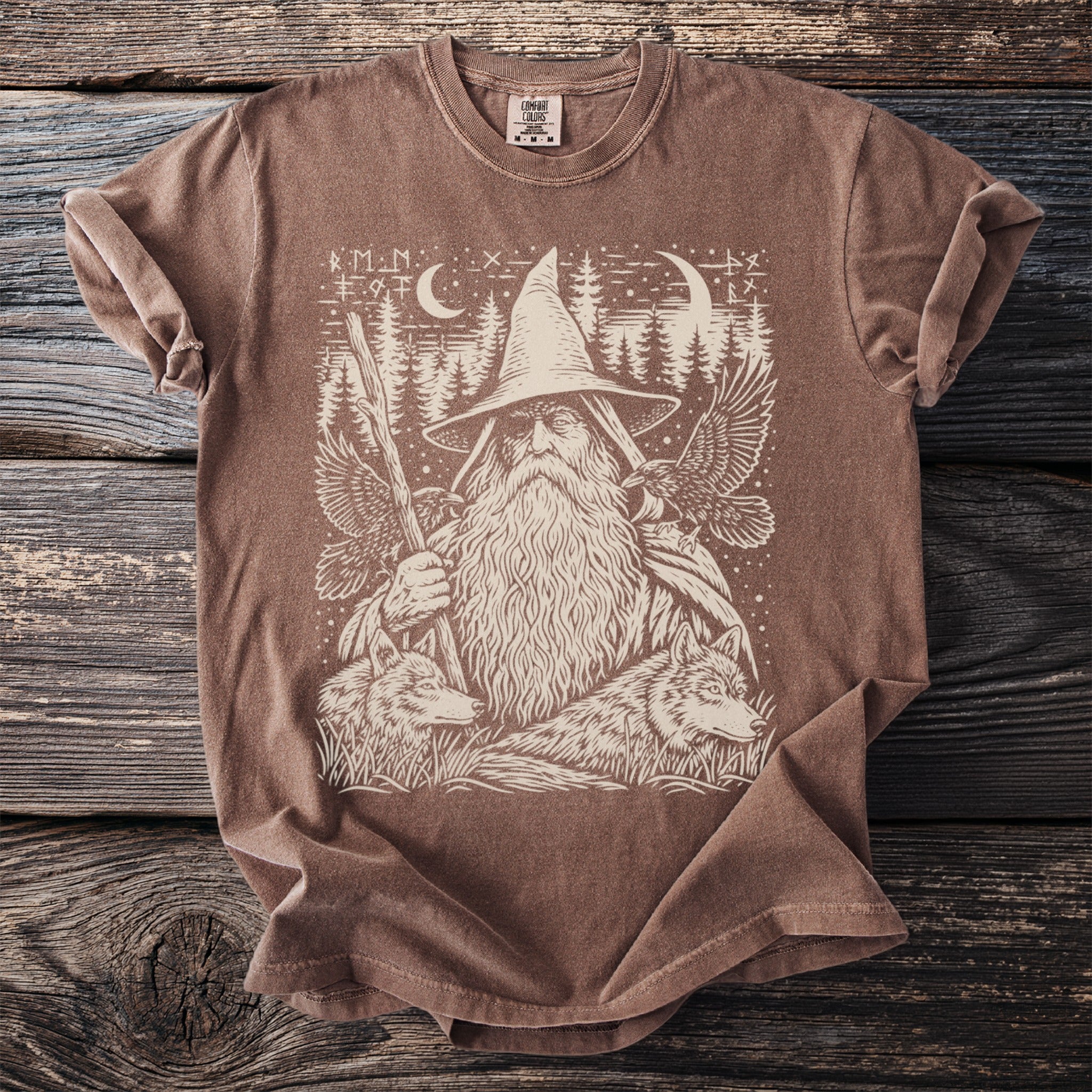 Brown t-shirt with a cream graphic of a wizard, wolves, eagles, and trees.