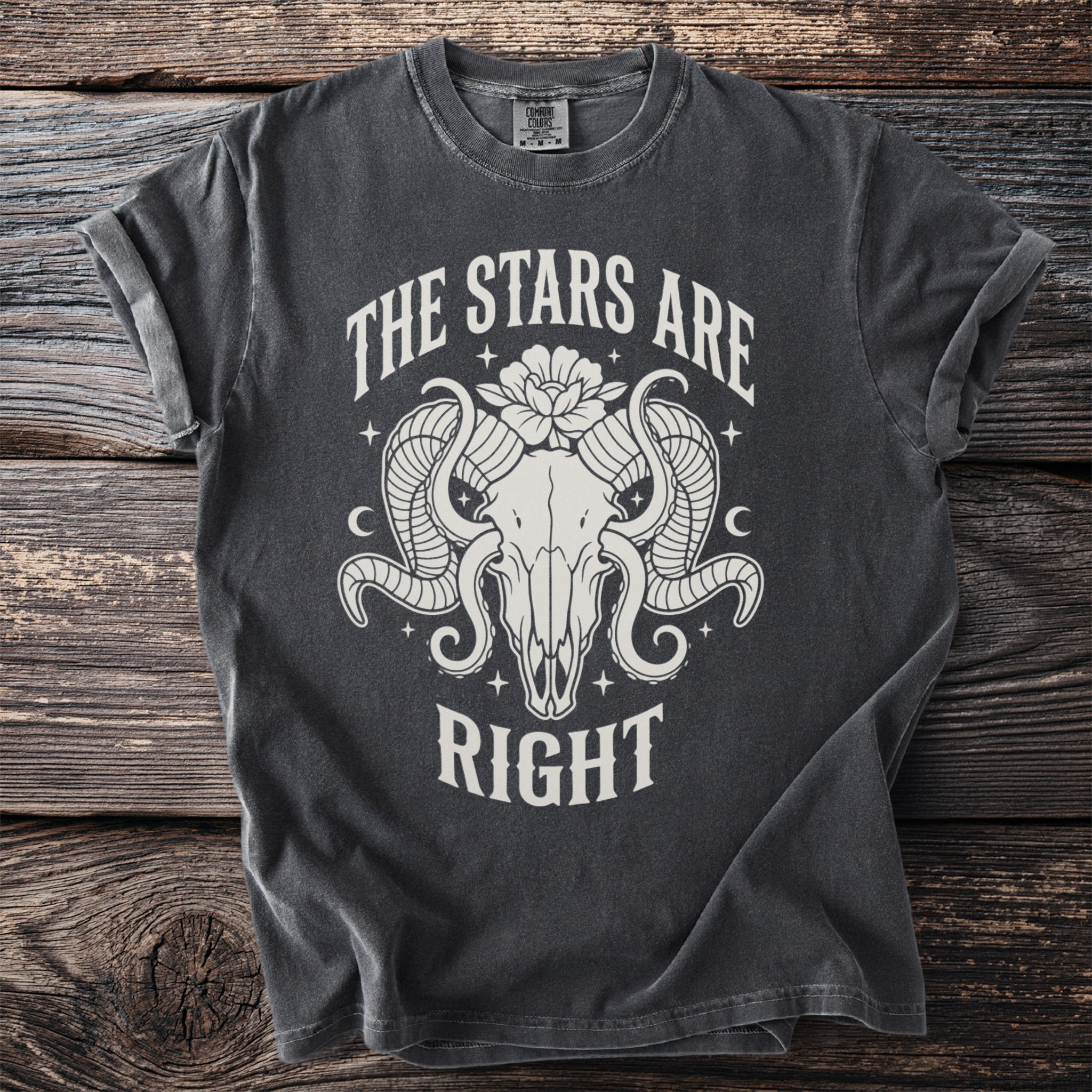 Dark grey t-shirt with white graphic of ram skull, flower, and text "The Stars Are Right".