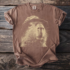 Brown t-shirt featuring a cream sketch of a capybara wearing a hat.